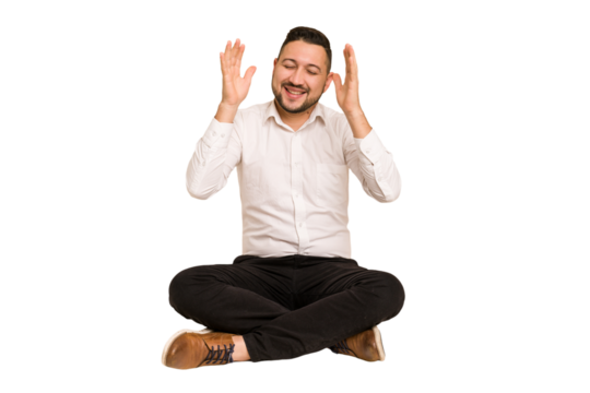 Adult latin man sitting on the floor cut out isolated joyful laughing a lot. Happiness concept.