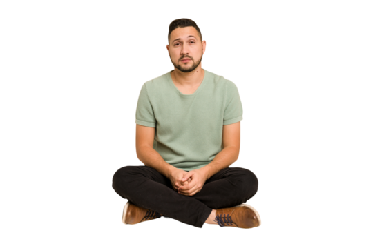Adult latin man sitting on the floor cut out isolated sad, serious face, feeling miserable and displeased.