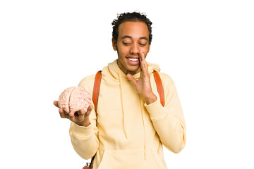 Young African American man holding a brain isolated is saying a secret hot braking news and looking...