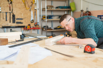 Carpenter measures wooden planks in the workshop.