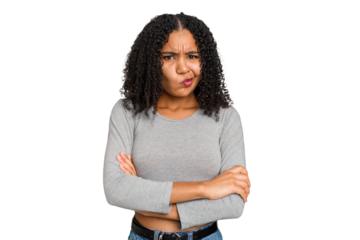 Young african american woman with curly hair cut out isolated frowning face in displeasure, keeps arms folded.