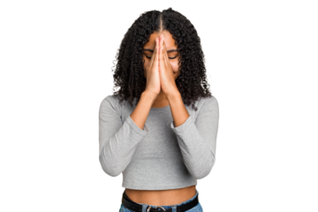 Young african american woman with curly hair cut out isolated holding hands in pray near mouth, feels confident.