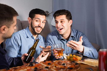 Friendly cheerful meeting in men company over beer with pizza at home