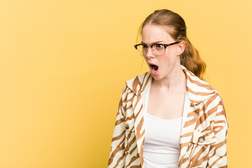 Young caucasian redhead woman isolated on yellow background shouting very angry, rage concept, frustrated.