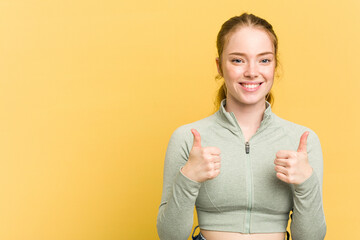 Young caucasian redhead woman isolated on yellow background smiling and raising thumb up