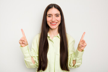 Young caucasian woman isolated on white background indicates with both fore fingers up showing a...