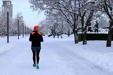 Fototapeta na wymiar Winter sport, healthy lifestyle. A man in sports uniform runs along winter street