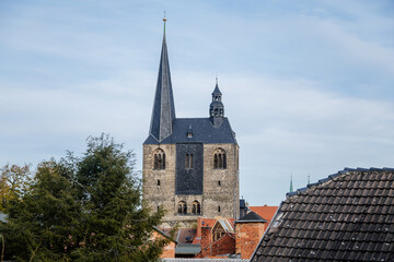 Fototapeta premium Quedlinburg, Saxony-Anhalt, Germany, 28 October 2022: Panoramic view of city from observation platform, old houses with red tiled roofs, tower and spire of St. Benedict church, sunny autumn day