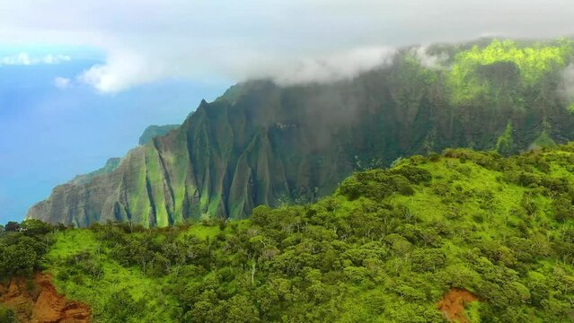 Drone shot flying over beautiful mountain ridge and clouds in rural jungle bush forest of Hawaii viewing the trees, plants, and mountains 4k parallax shot
