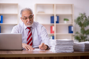 Fototapeta premium Old male employee and too much work in the office