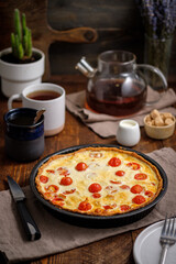Creamy shortbread pie. Quiche with cherry tomatoes and chicken in the village on a wooden table.