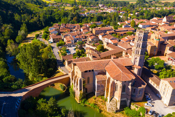 Picturesque summer view from drone of French township of Rieux-Volvestre on banks of Arize river with Gothic building of medieval Cathedral, Occitanie