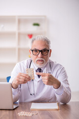 Old male doctor suggesting pills at the hospital