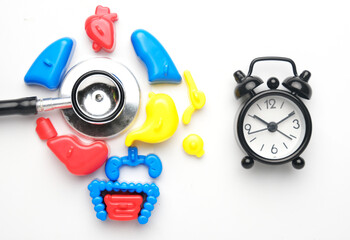 Flatlay picture of toy human organ stethoscope and alarm clock on white background. Regular medical...
