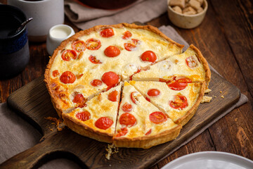 Creamy shortbread pie. Quiche with cherry tomatoes and chicken in the village on a wooden table.