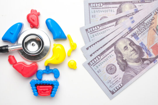 A flatlay picture of toy human organ, stethoscope and fake money. Medical expenses and medicare advantage concept.
