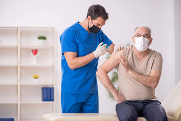 Old male patient visiting young male doctor in vaccination conce