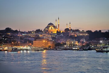 Obraz premium A cruise ship with the background of historic old Istanbul as the sun sets over the bosphorous straits in Istanbul, Turkey 