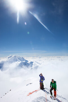 Climbers and rangers Dave Weber and Tom Ditolla are on a snow ridge of the West Rib high on Mount McKinley. Dave is pointing to the summit, Mount Hunter is seen in the background.