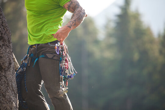 Rock climber reaching for cam from rack while climbing