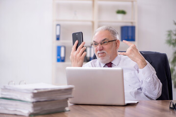 Obraz premium Old male employee and too much work in the office