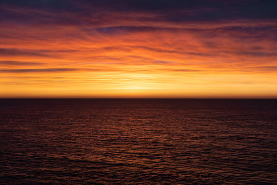 Orange and pink sky above ocean horizon