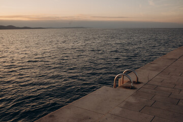 Fototapeta na wymiar promenade along the adriatic sea with stairs to the sea at sunset