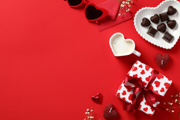 Valentine's Day background. Gift, envelope, heart shaped cup of coffee, candy on red table . Valentines day concept. Flat lay, top view