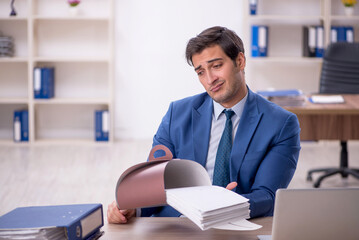Young male employee eating cake at workplace
