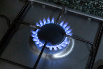 Closeup shot of blue fire from domestic kitchen stove top. Gas cooker with burning flames of propane gas. Industrial resources and economy concept.