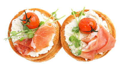 Tasty organic rusks with prosciutto, cream cheese and tomatoes on white background, top view