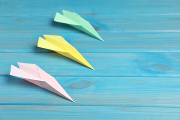 Handmade paper planes on light blue wooden table. Space for text