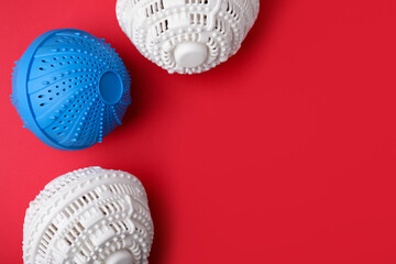 Laundry dryer balls on red background, flat lay. Space for text