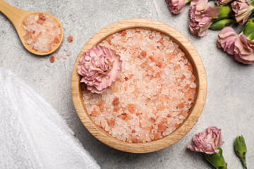 Bowl with natural sea salt, spoon and beautiful flowers on light grey table, flat lay