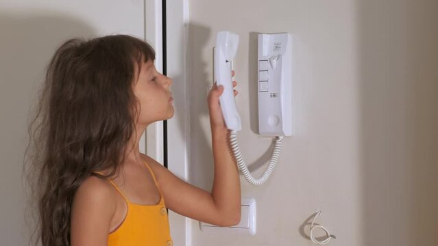 Use intercom device. A view of smart child take her intercom device to open the door in the hotel.