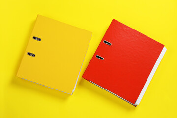 Office folders on yellow background, flat lay