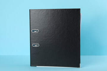 Black hardcover office folder on light blue background