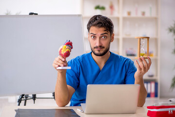 Young male doctor cardiologist in time management concept