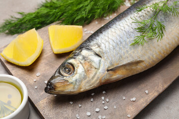 Board with delicious salted herring, dill, lemon and olive oil on grey table, closeup