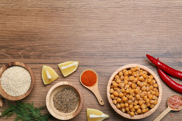 Delicious chickpeas and different products on wooden table, flat lay with space for text. Hummus ingredients