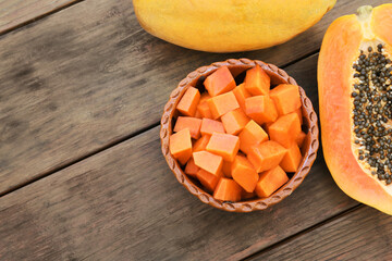 Tasty cut and whole papaya fruits on wooden table, flat lay. Space for text