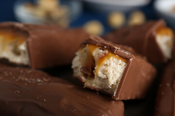 Tasty chocolate bars with caramel on blurred background, closeup view