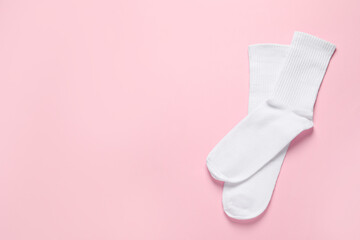 Pair of white socks on pink background, flat lay. Space for text