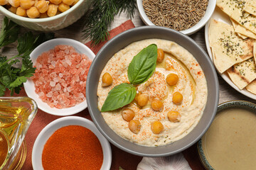 Delicious creamy hummus with chickpeas and different ingredients on wooden table, flat lay