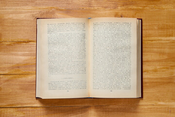 Open old hardcover book on wooden table, top view