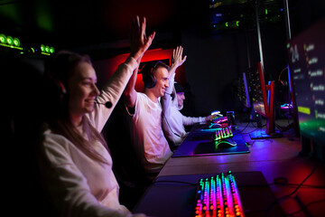 esports team plays in a computer club and rejoices in victory, people give five to each other and...