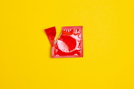 torn pack of a condom lies on a yellow background, the concept of safe sex