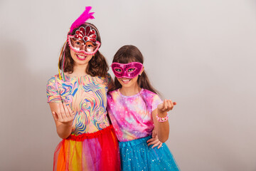 two Brazilian children, girls, dressed in carnival clothes, inviting with their hands.