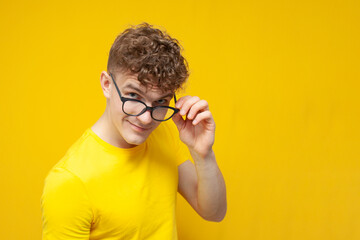 curly smart guy in glasses looks at the camera and flirts