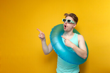 young guy in sunglasses and with an inflatable swim ring in the summer on vacation shows surprise